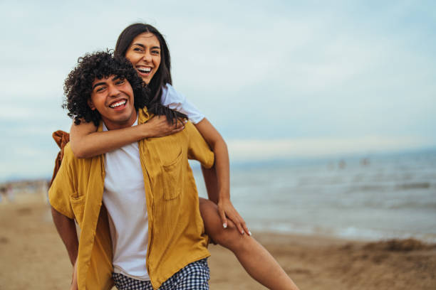 istock Joyful Hispanic Couple Enjoying Piggyback Ride on Beach 2158285324