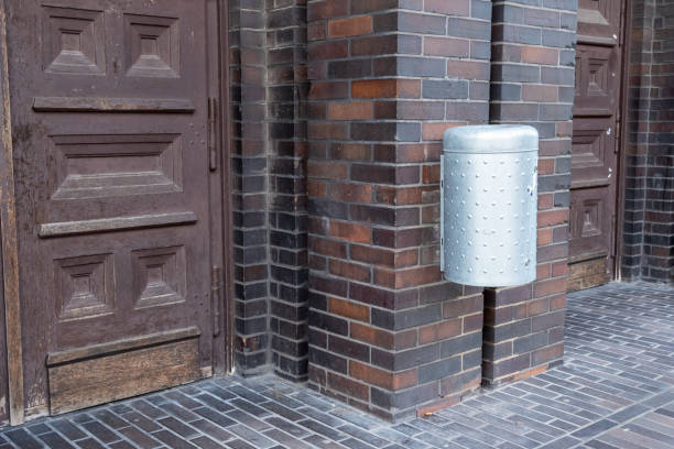modern stainless steel wastepaper basket on an old brick building