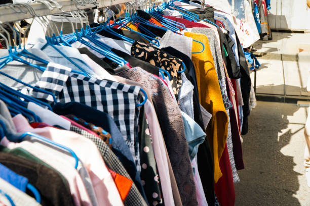 Flea market, colorful second hand children jackets hanging on metal rack, used clothing, secondhand fashion outdoor sale.
