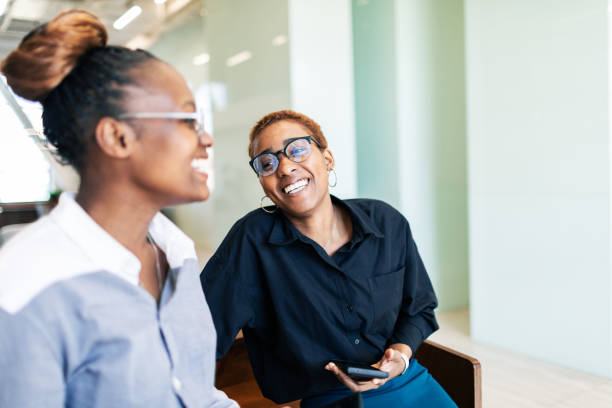 Two black colleagues taking a break and talking in office