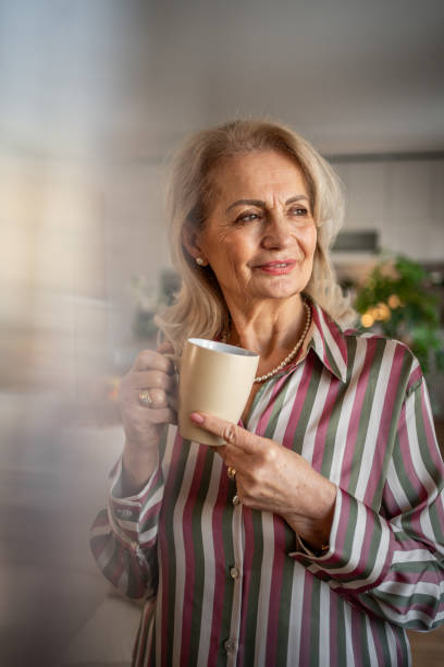 istock Elderly retired woman drinking coffee and relaxing at home 2158292677