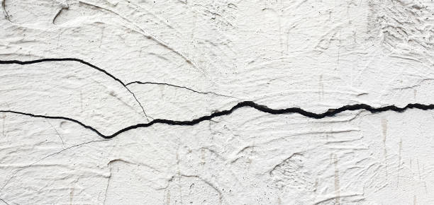 Cracked plaster. Damaged plastered, concrete wall in chips, cracks