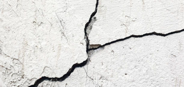 istock Cracked plaster. Damaged plastered, concrete wall in chips, cracks 2158300856