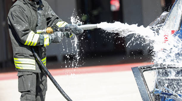 istock firefighter extinguishes a burning car with foam after a road accident 2158301195