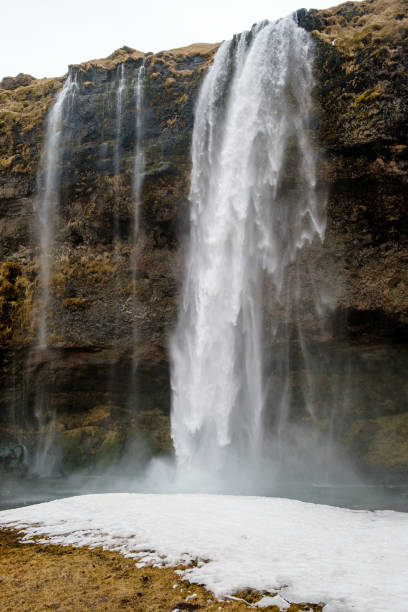 istock Majestic Waterfall Cascading Over Rocky Cliff in Winter Landscape 2158303210