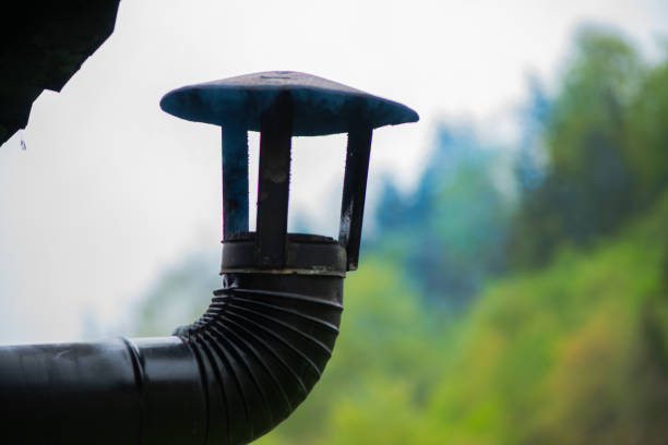 A scenic view of a village chimney with smoke rising in nature, showcasing the rustic charm and peaceful atmosphere of rural life.