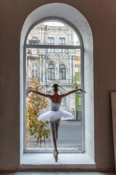 istock Ballerina poses en pointe, white tutu within an arched window frame, juxtaposing the refined beauty 2158310986
