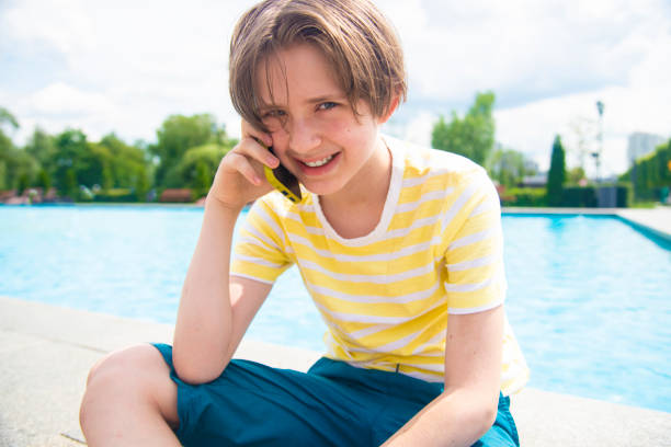 istock 11 year old boy communicates on a smartphone while sitting in front of the pool on vacation during the holidays 2158312278