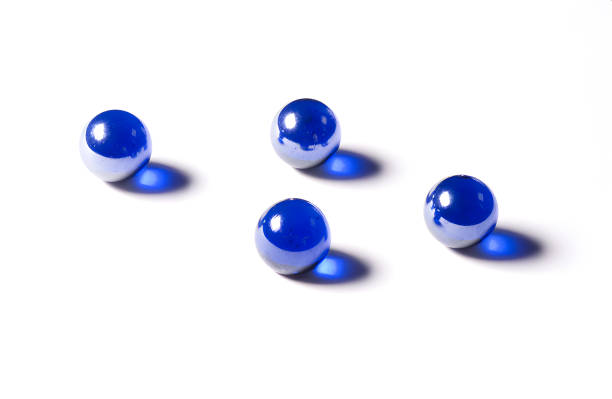 Four shiny and reflective blue marbles with shadows on a white background.