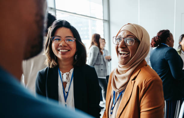 female colleagues interacting at a corporate workshop with happy smiles and engaging conversations - multietnisk grupp bildbanksfoton och bilder