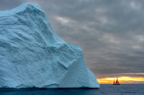 istock Large Iceberg with sail red sail boat 2158323404