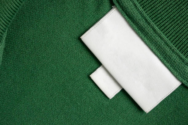 istock Blank white laundry care clothes label on green shirt fabric texture background 2158333617