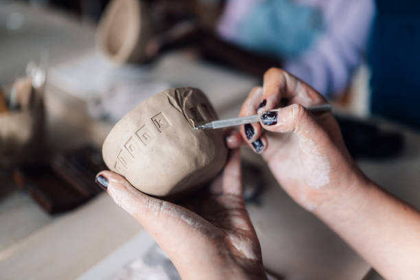 istock Close up of attendee's hands using pottery tool for decorating clay mug 2158334172