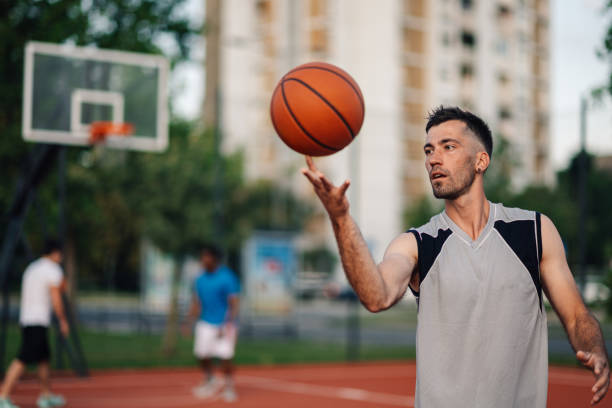 istock Focused player spinning basketball while playing on an outdoor court 2158334214