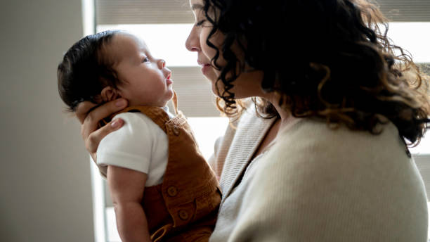 Young Hispanic mother cares for her newborn infant son