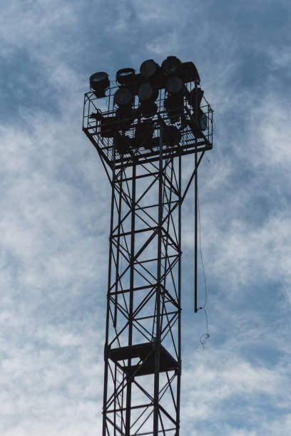 istock A tall metal tower rises against a slightly cloudy sky. Several floodlights are located on the tower. Perspective from the ground, emphasising the height and structure of the tower. 2158334941