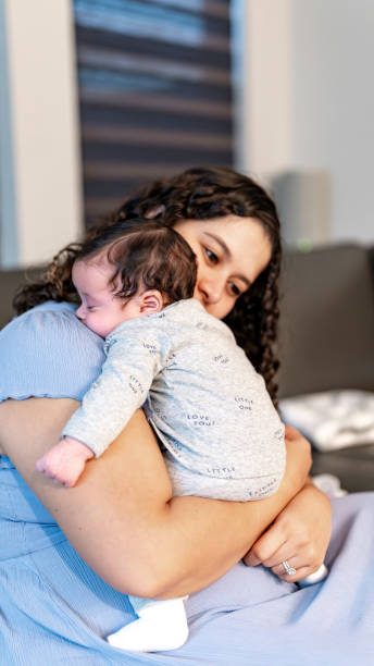 istock Young Hispanic mother cares for and bonds with her sleeping newborn infant son 2158335573