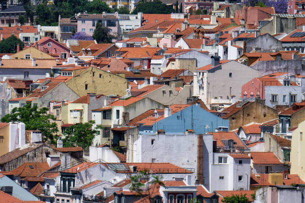 aerial view of the white and pastel-colored old buildings with red-tiled roofs in the charming, winding old town of lisbon