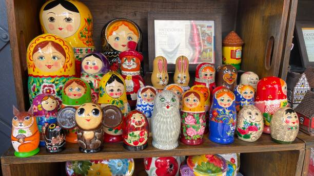 Brightly painted population of wooden Matryoshka or Babuska stacking dolls. Varying sizes. Females faces with red lipstick and rosy cheeks. Girls in traditional floral dresses and scarfs painted population of wooden Matryoshka or Babuska stacking dolls. Varying sizes. Females faces with red lipstick and rosy cheeks. Girls in traditional floral dresses and scarfs babuska stock pictures, royalty-free photos & images