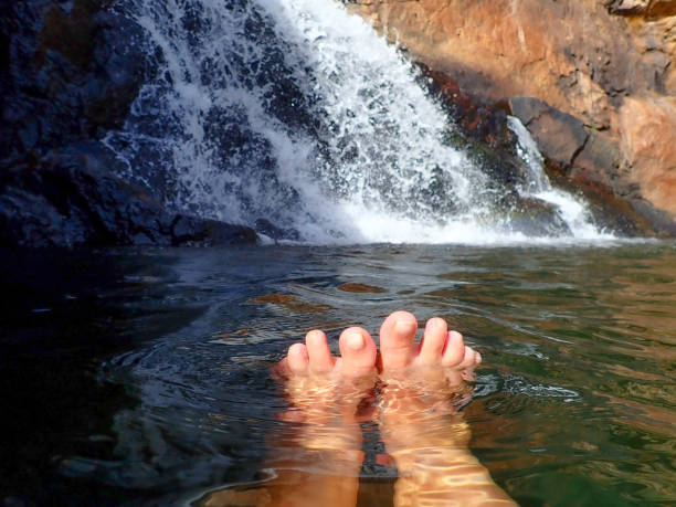 istock Swimming in water hole with waterfall showing feet 2158341623
