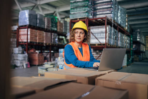 istock Focused and Efficient: A Female Warehouse Manager Coordinates Operations via Laptop 2158342193