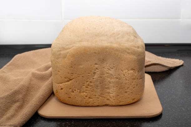 istock Freshly baked white bread from a bread machine on a wooden board, on a black countertop 2158344591