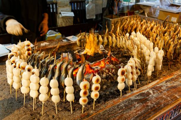 istock Around a charcoal fire, a stall vendor roasting skewered Iwana fish and Kushi Dango, which is made from rice flour and a street-food popular with Japanese people (in Yumoto, Oku-Nikko, Tochigi, Japan) 2158346357