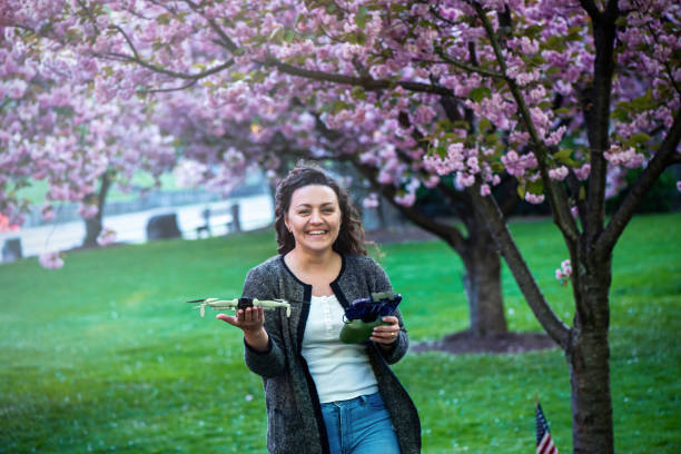 Smiling woman holding drone and remote control in park.