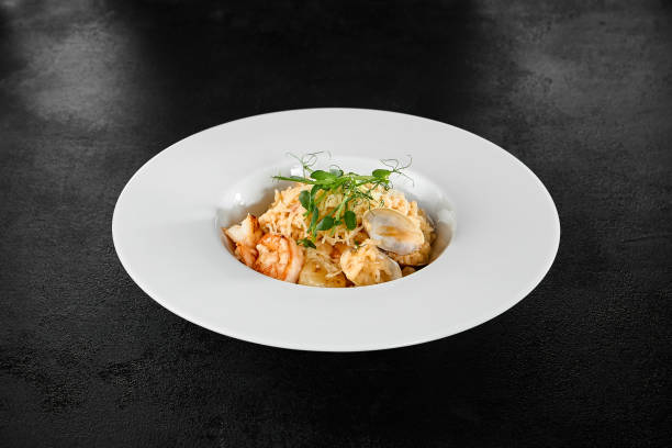 istock Seafood Risotto with Scallops and Shrimp in Elegant White Bowl on Dark Background 2158358735