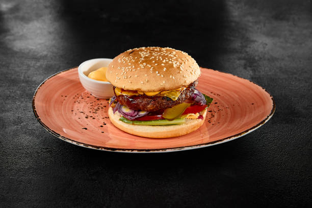 istock Delicious Beef Burger with Cheese, Pickles, and Onion on Rustic Plate 2158358737