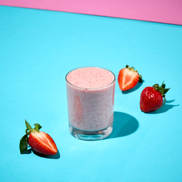 Strawberry Smoothie in a Glass with Fresh Strawberries on a Vibrant Colored Background