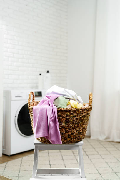 istock Laundry Basket With Clean Clothes Sitting on White Stool in Laundry Room 2158359418