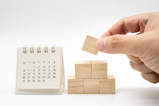 istock Hand putting and stacking blank wooden cubes on white background  with copy space for input wording and infographic icon. Wooden blocks with Calendar. 2158360583