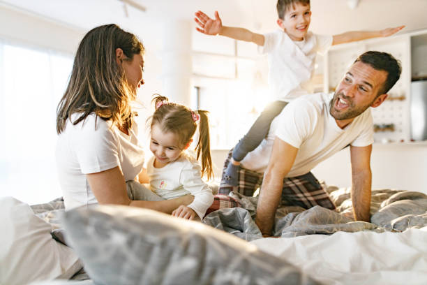 istock Playful parents having fun with their small kids during morning time on a bed. 2158362485
