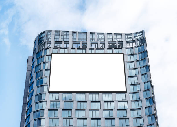 istock Mock up white horizontal large LED display billboard on tower building with blue sky background clipping path for mockup 2158362899