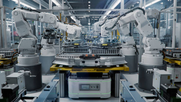 istock Industrial Robot Arms Assemble Lithium-Ion EV Battery Pack. Electric Car Manufacturing Inside Automotive Smart Factory. Row of White Robotic Arms at Automated Production Line at Bright Modern Factory. 2158369971