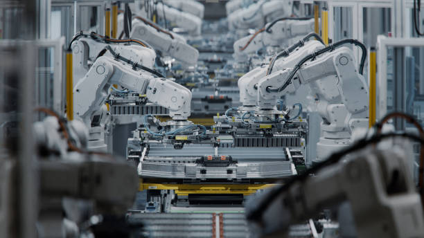 istock Lithium-Ion EV Battery Pack Production at Large Automated Assembly Line at Bright Factory Equipped With Industrial Robot Arms. Electric Car Manufacturing. Row of White Robotic Arms at Factory 2158369972