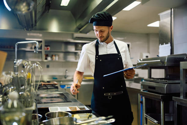 istock Male chef taking notes while going through food supplies in the kitchen. 2158371396