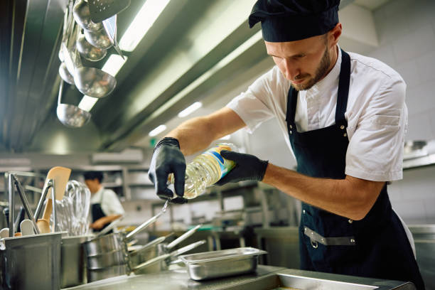 istock Chef pouring oil while preparing food in the kitchen. 2158371582