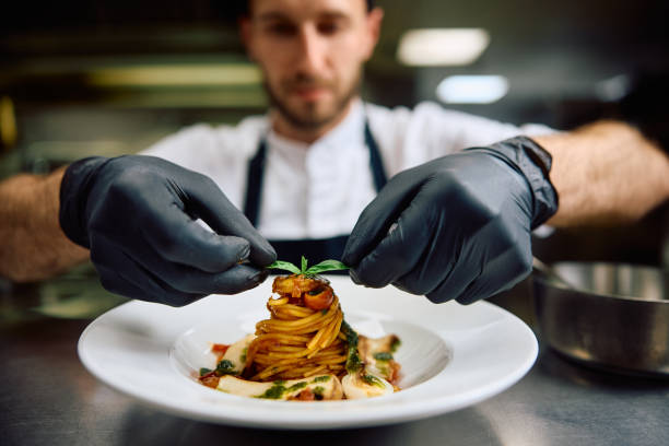 istock Close up of chef decorating dish while serving food in restaurant. 2158371662