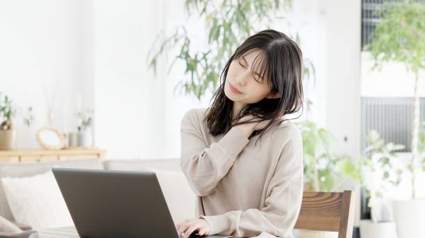 a woman who feels stiff shoulders while working on a computer - 仕事 つらい 日本人 ストックフォトと画像