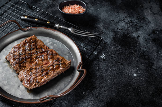 istock Alternative choice steak - Grilled Skirt or Machete beef meat.  Black background. Top view. Copy space 2158372892