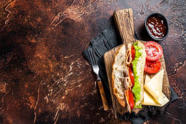 istock Smoked turkey sandwich with ham, cheese, tomato and Lettuce. Dark background. Top view. Copy space 2158372950