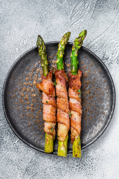 istock Plate with pork bacon wrapped asparagus on grey table. White background. Top view 2158373018