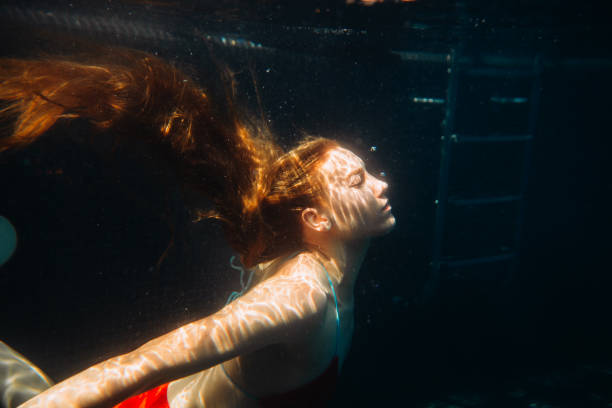 istock Young redheaded woman swimming underwater in a pool 2158373506