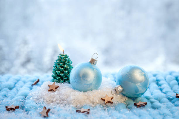 Selective focus on blue color Christmas bauble and spruce shape candle burning, blur background. Still life, lot of copy space.
