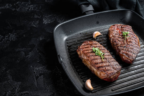 istock Grilled Top Blade or flat iron roast beef meat steaks on a skillet. Black background. Top View. Copy space 2158374829