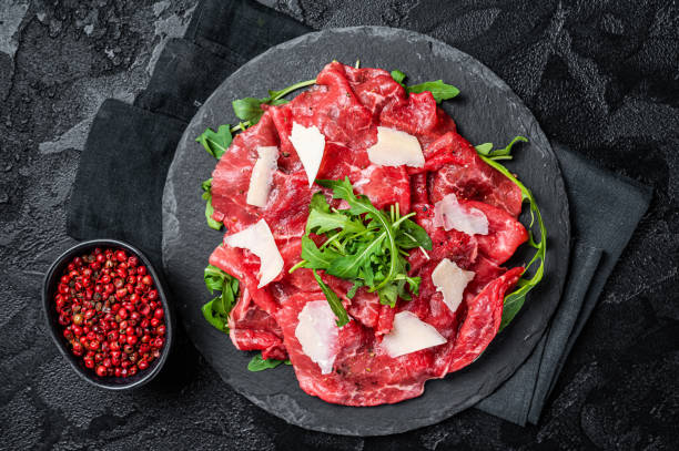 istock Beef carpaccio with arugula, parmesan cheese. Black background. Top view 2158376304