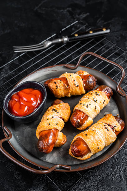 istock Pigs in Blanket puff pastry sausage wrap roll. Black background. Top view 2158376387