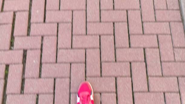 Man walks along a tiled sidewalk. First-person view